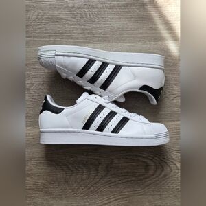 Adidas Superstar sneakers in white with black stripes and gold accents. 